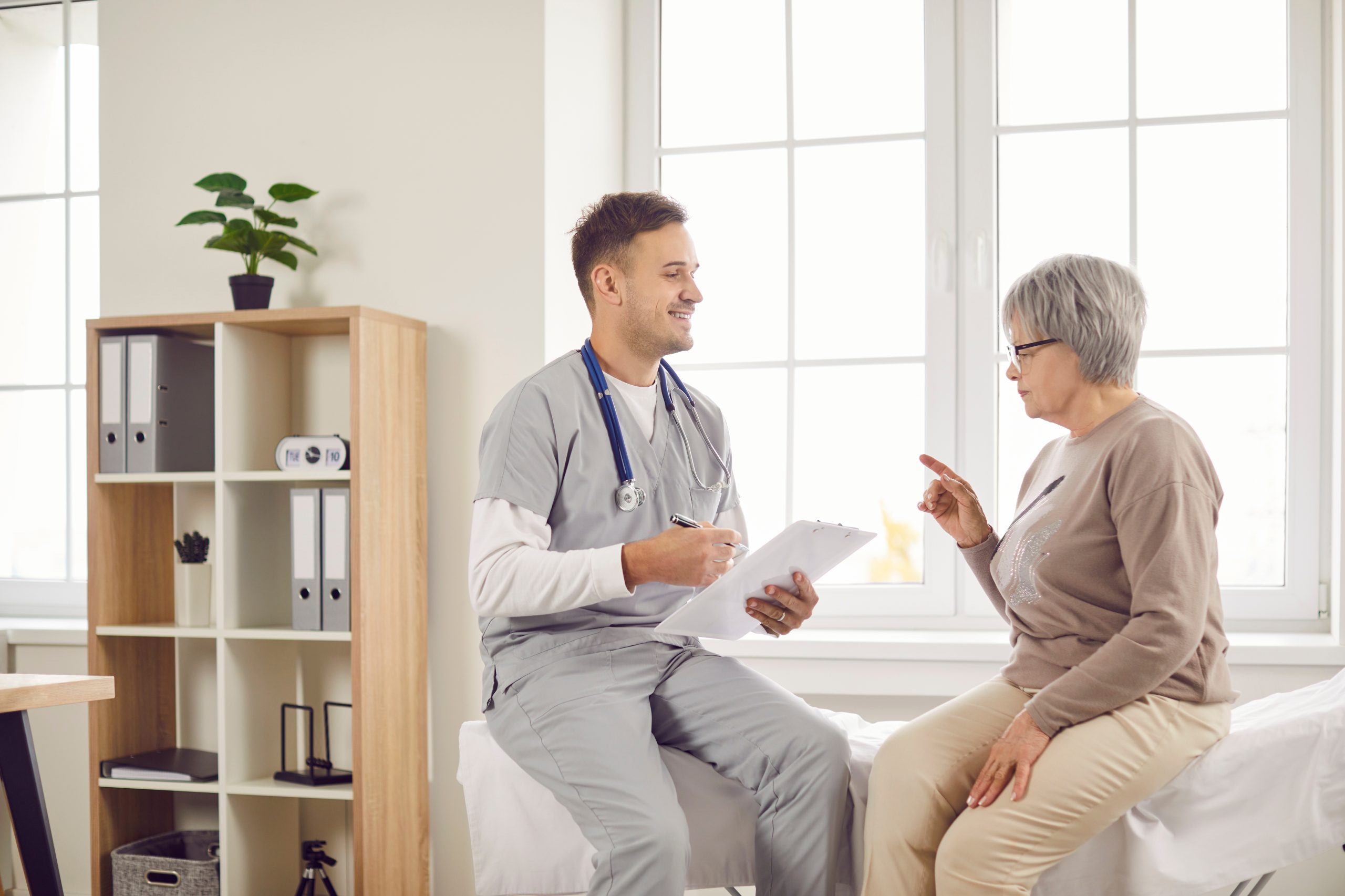 Young,Happy,Doctor,,Male,Nurse,And,Old,Woman,Talking,,Explaining, Infermiere a Domicilio Roma: scopri i servizi e le modalità di erogazione di ADI Salus
